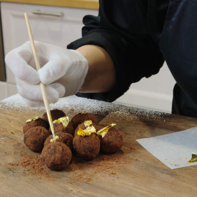 Mini chocolate truffles being dusted with golden flakes